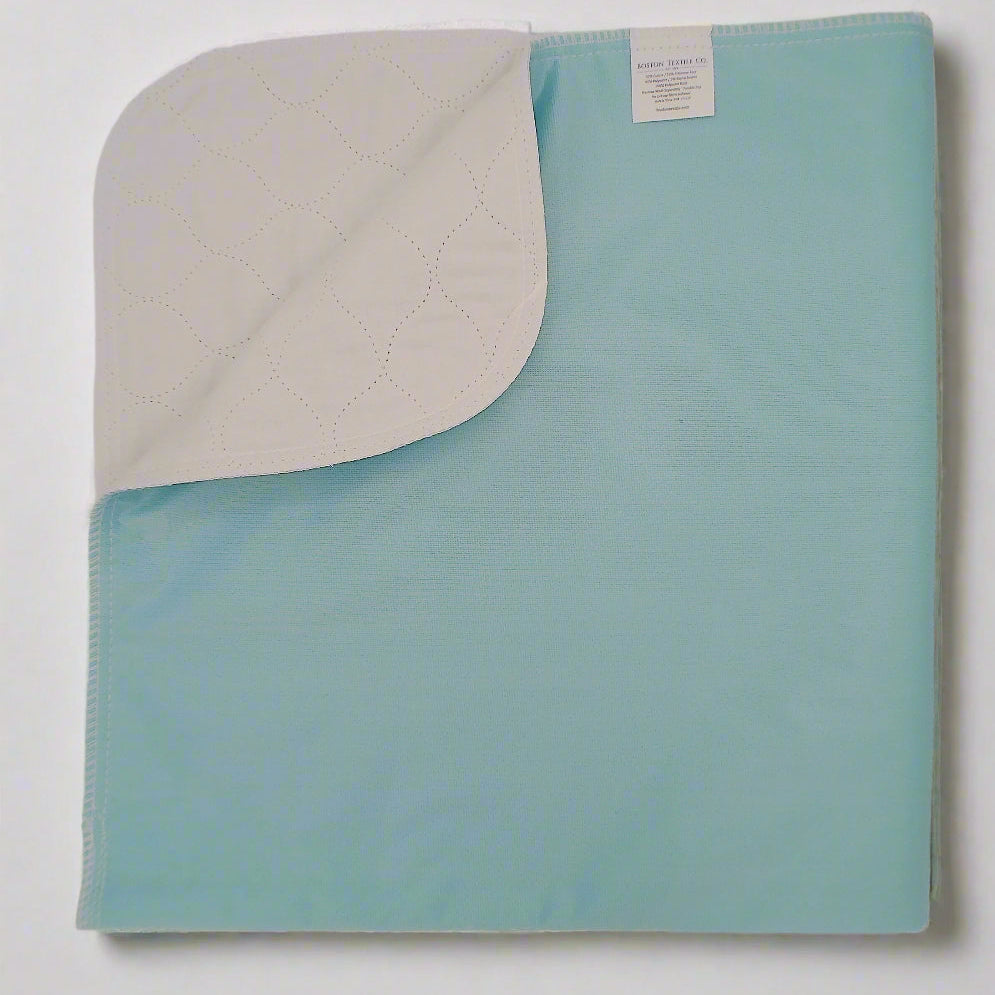 Pictured: A green premium twill underpad with a white leakproof barrier and a tag visible on the upper corner. The underpad lies against a white background.