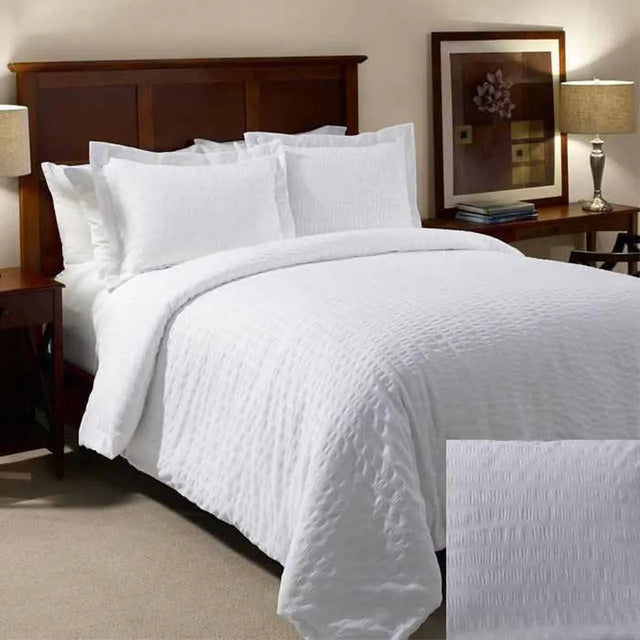 White textured bed set. Hotel bed showcases a king bed with big fluffy pillows and large oversized duvet.