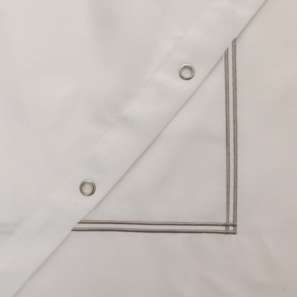 Close-up of a beige fabric with metal eyelets on a white background
