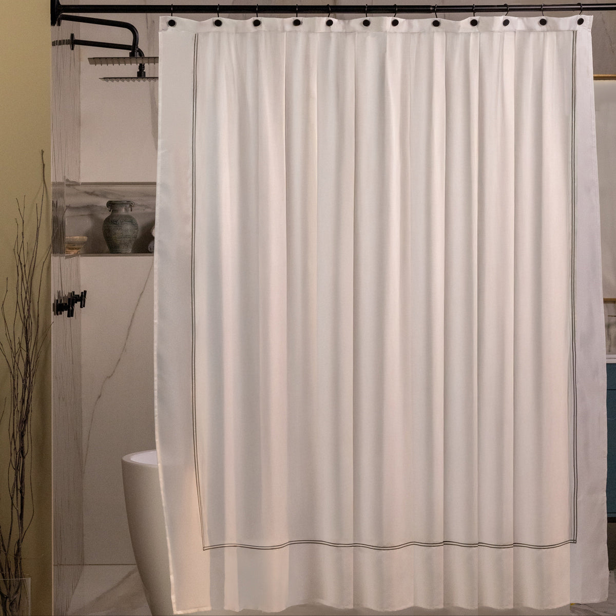 Pictured: Modern bathroom with a free standing tub in a large standing shower. On the curtain rod is the Embroidered Shower Curtain, which is white with taupe embroidering.