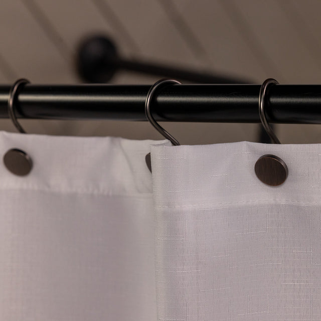 Close-up of a shower curtain with a black rod and hooks, featuring a neutral background.