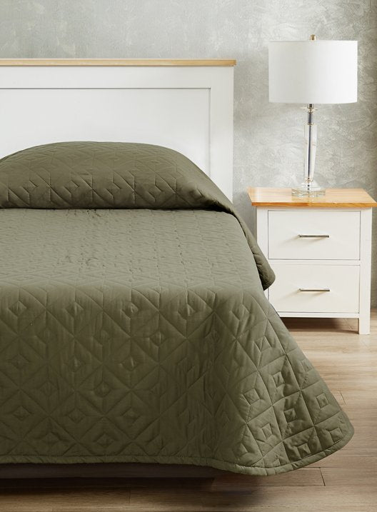 Pictured: Nicely made bed on a white wooden bed frame with a matching nightstand and lamp to the right. The bed features the CozyCare DESIGNS Bedspread in the shade "Moss".