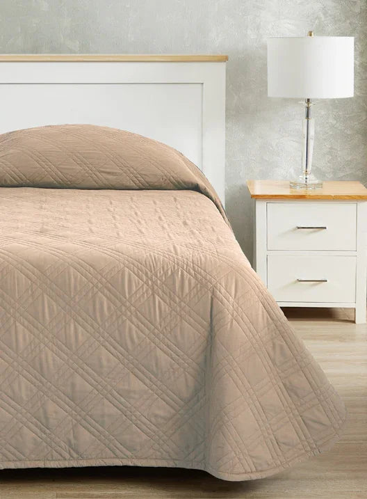 Taupe colored bedspread coverlet for single bed. Bed has white frame with wood detailing. Matching nightstand to the right with metal lamp on top.