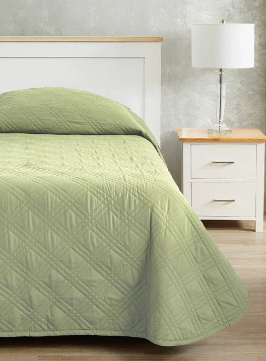 Spa green colored bedspread coverlet for single bed. Bed has white frame with wood detailing. Matching nightstand to the right with metal lamp on top.