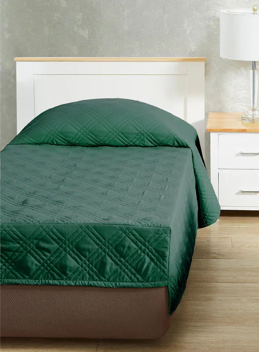 Forest green colored fitted coverlet for single bed. Bed has white frame with wood detailing. Matching nightstand to the right with metal lamp on top.