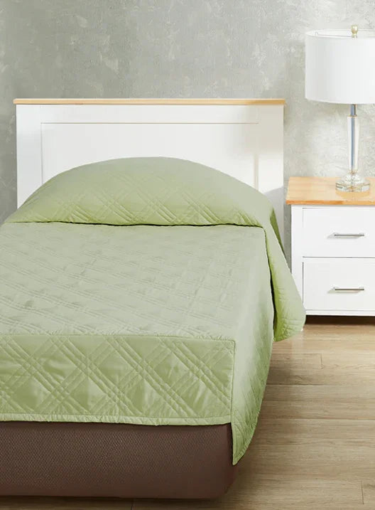 Matcha green colored fitted coverlet for single bed. Bed has white frame with wood detailing. Matching nightstand to the right with metal lamp on top.
