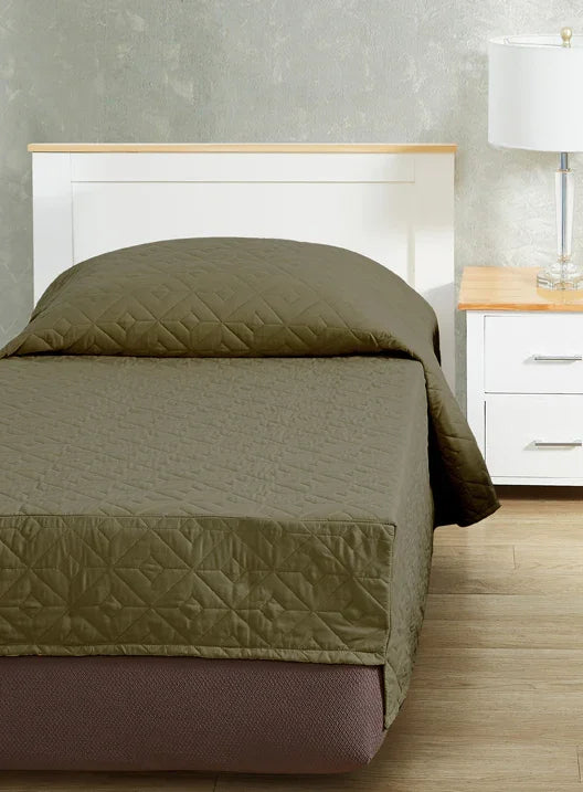 Khaki green colored bedspread coverlet for single bed. Bed has white frame with wood detailing. Matching nightstand to the right with metal lamp on top.