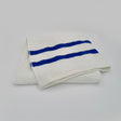 A white pool towel with two blue horizontal stripes on one end, neatly folded.