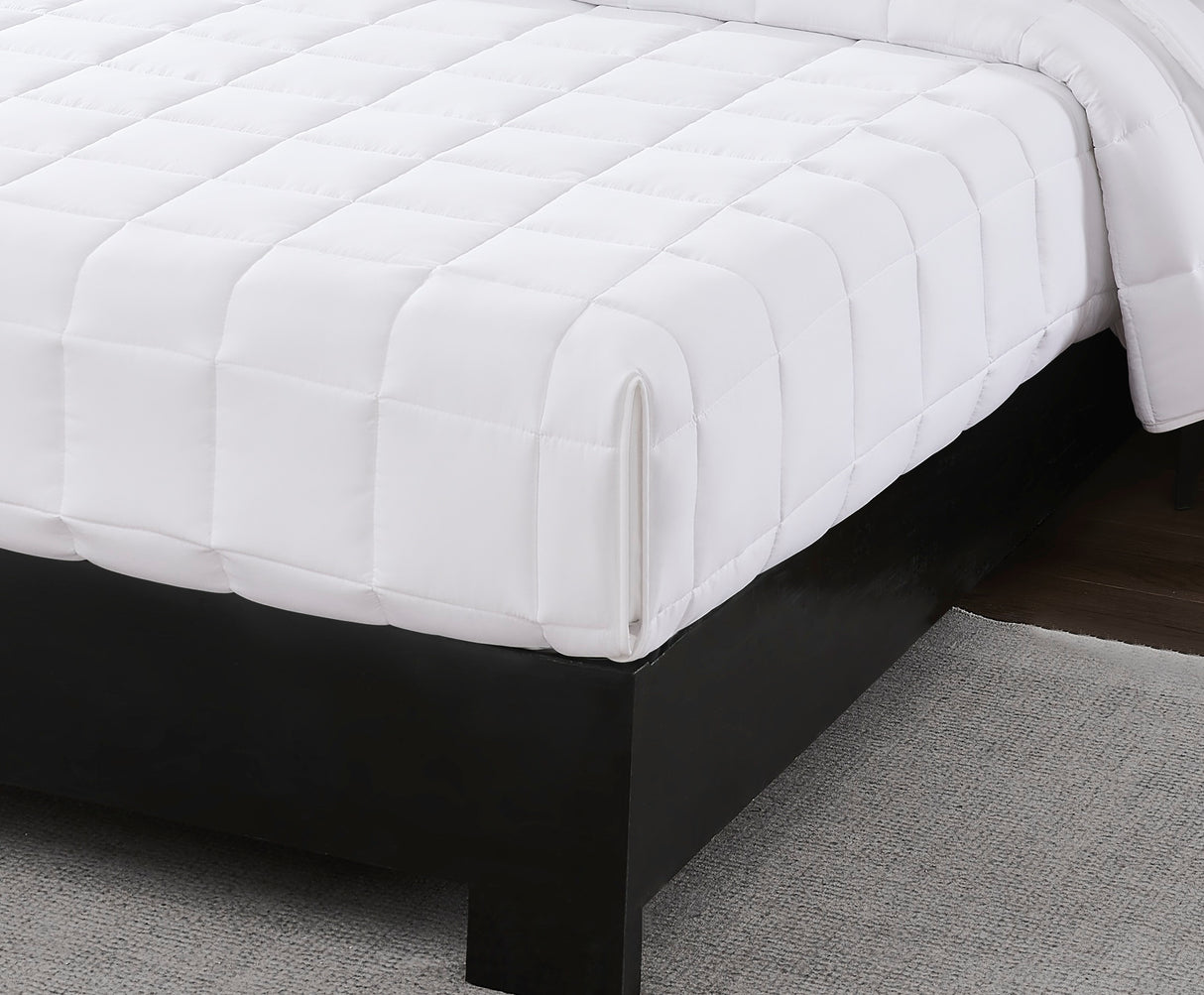 White mattress cover on a bed with a dark wooden frame.