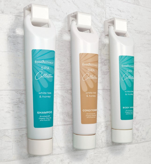 Ecolux Alta Brackets help hold all bulk hotel amenities from the EcoBotanics collection. Displayed on a marble tile wall.
