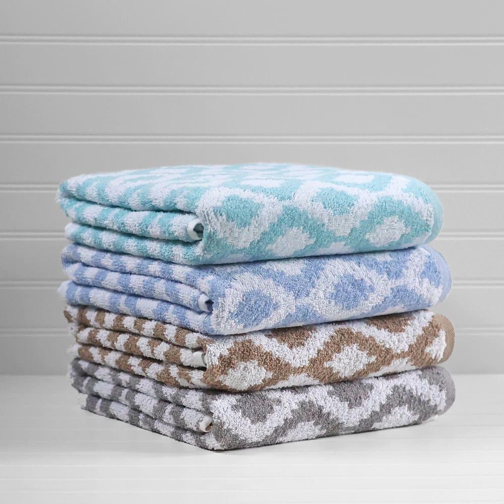 Product shot of diamond pattern towels in a variety of colors stacked on top of eachother. From top to bottom the colors include; teal, blue, brown and grey