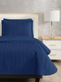 Dark blue colored bed sheet coverlet set for a single bed. White bedframe with wood detailing. Matching nightstand with metal lamp on top.
