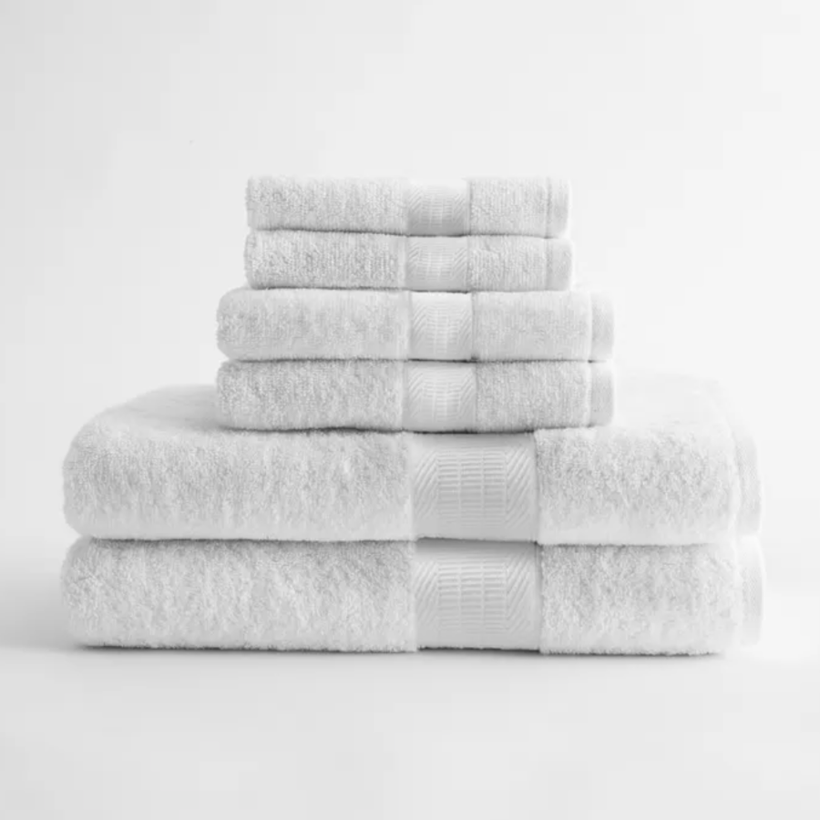 Pictured: Stack of white towels with a dobby border, representing the Levant Zero Twist Towel Collection. Stacked from largest to smallest against a white background.