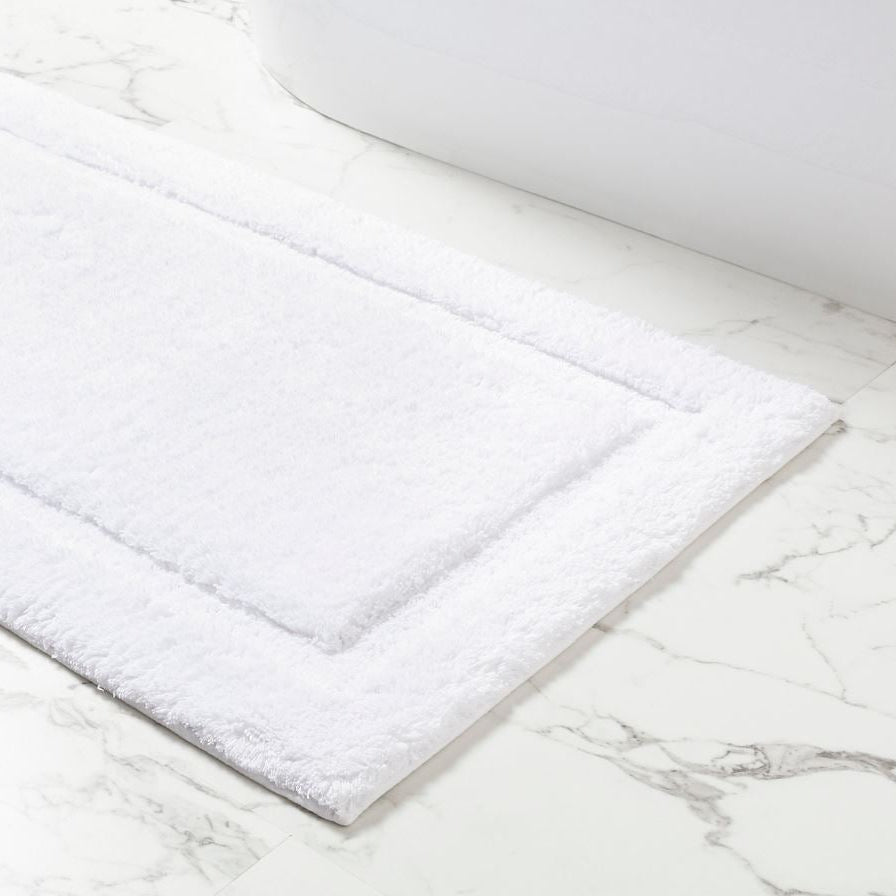 Pictured: Gryphon White Bath Rug laid out on a white marble floor.