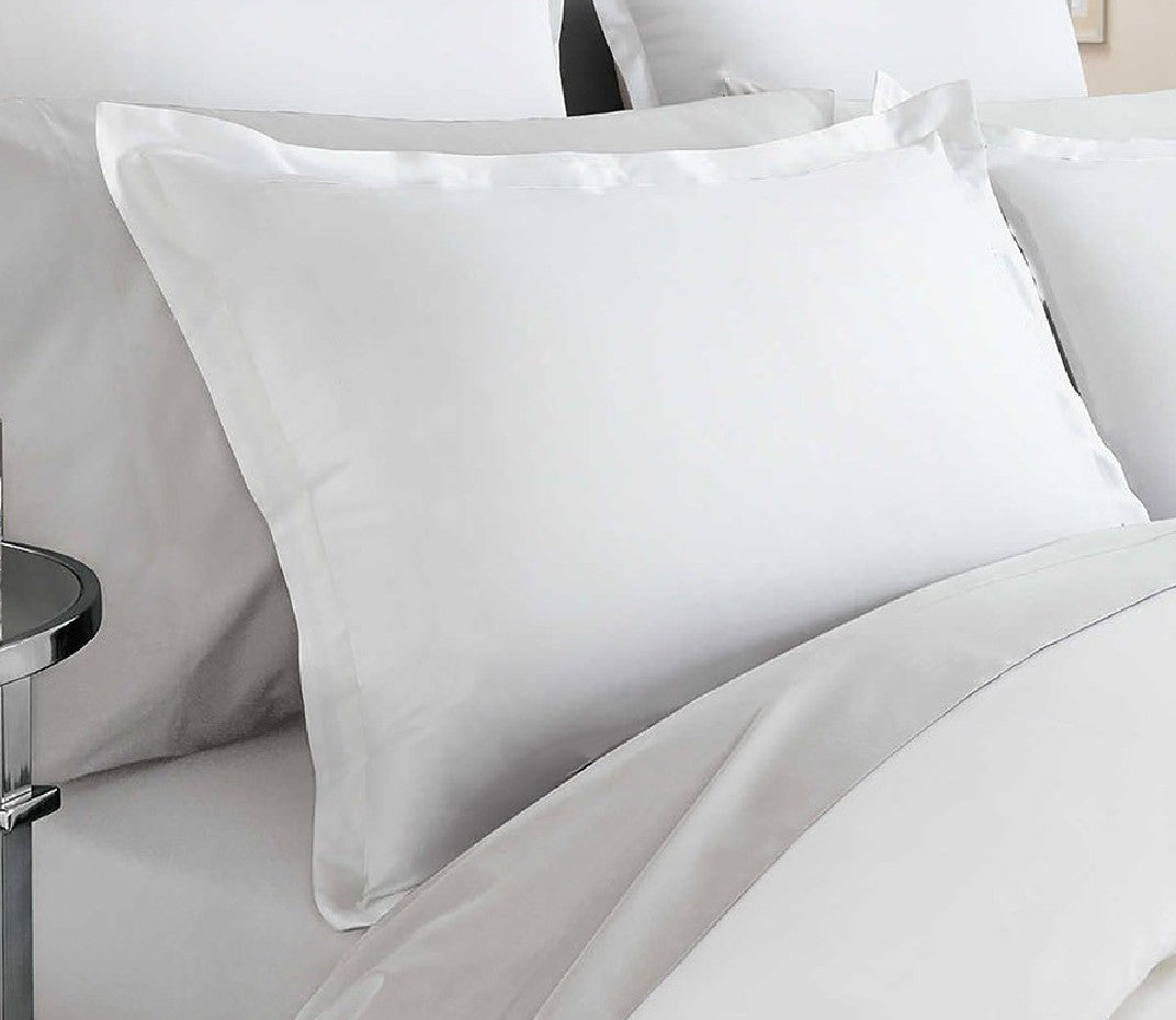White pillows on a bed with a side table in the background
