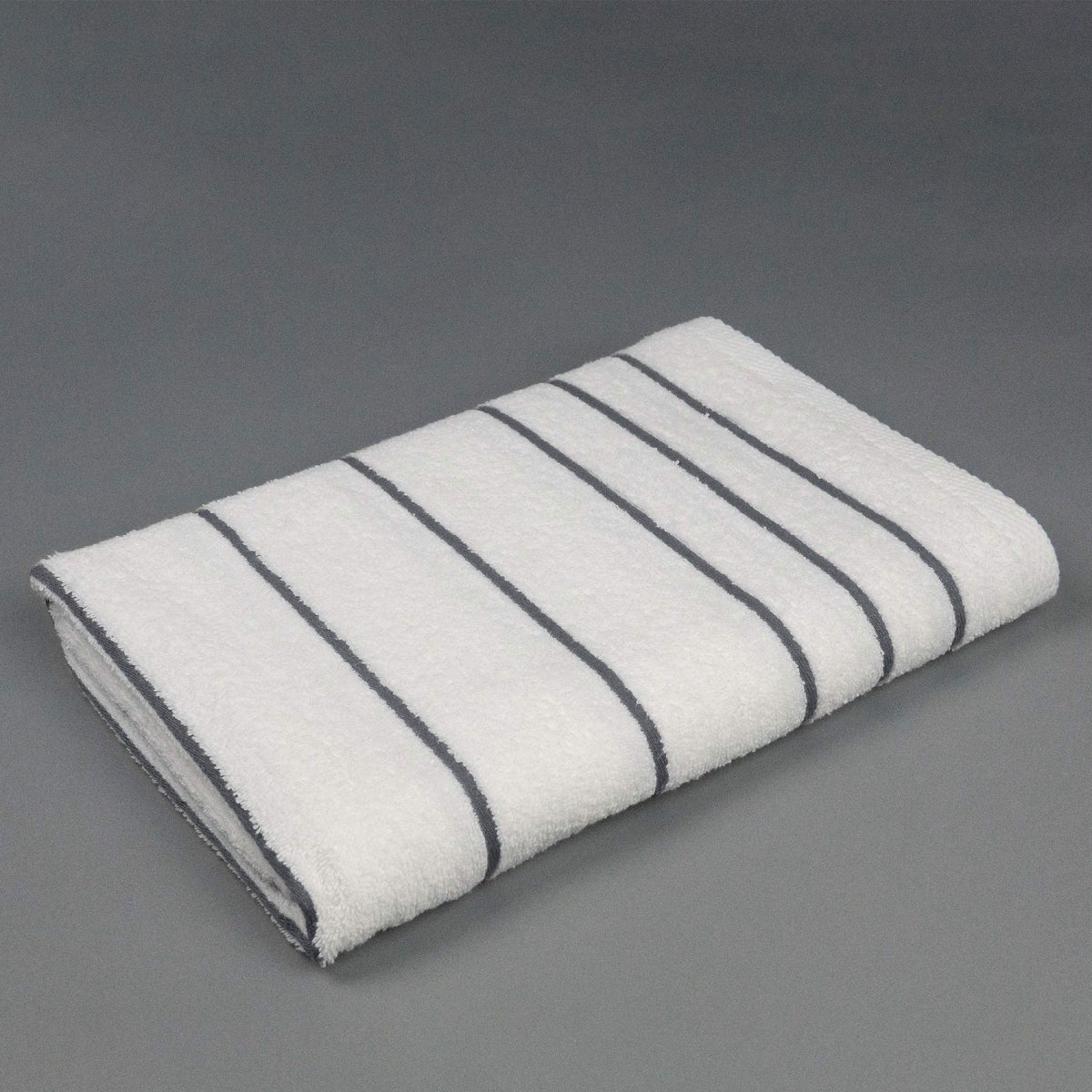 Pictured: The Grey Stripe Martex Resort Towel neatly folded and placed against a gray background.
