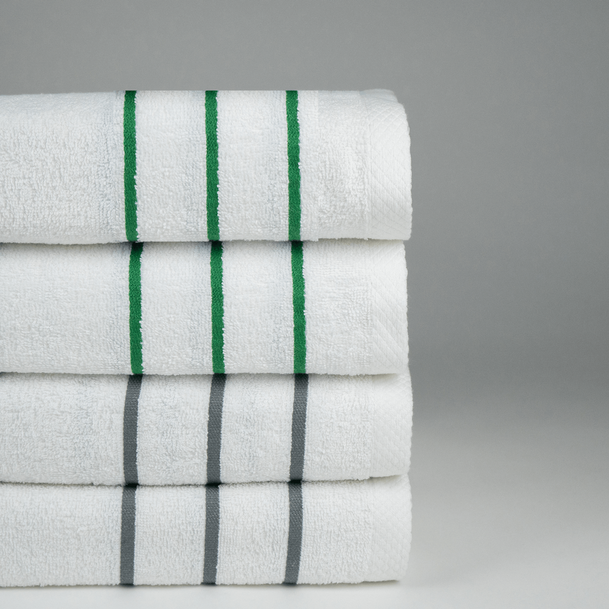 Stack of white pool towels with green and grey stripes