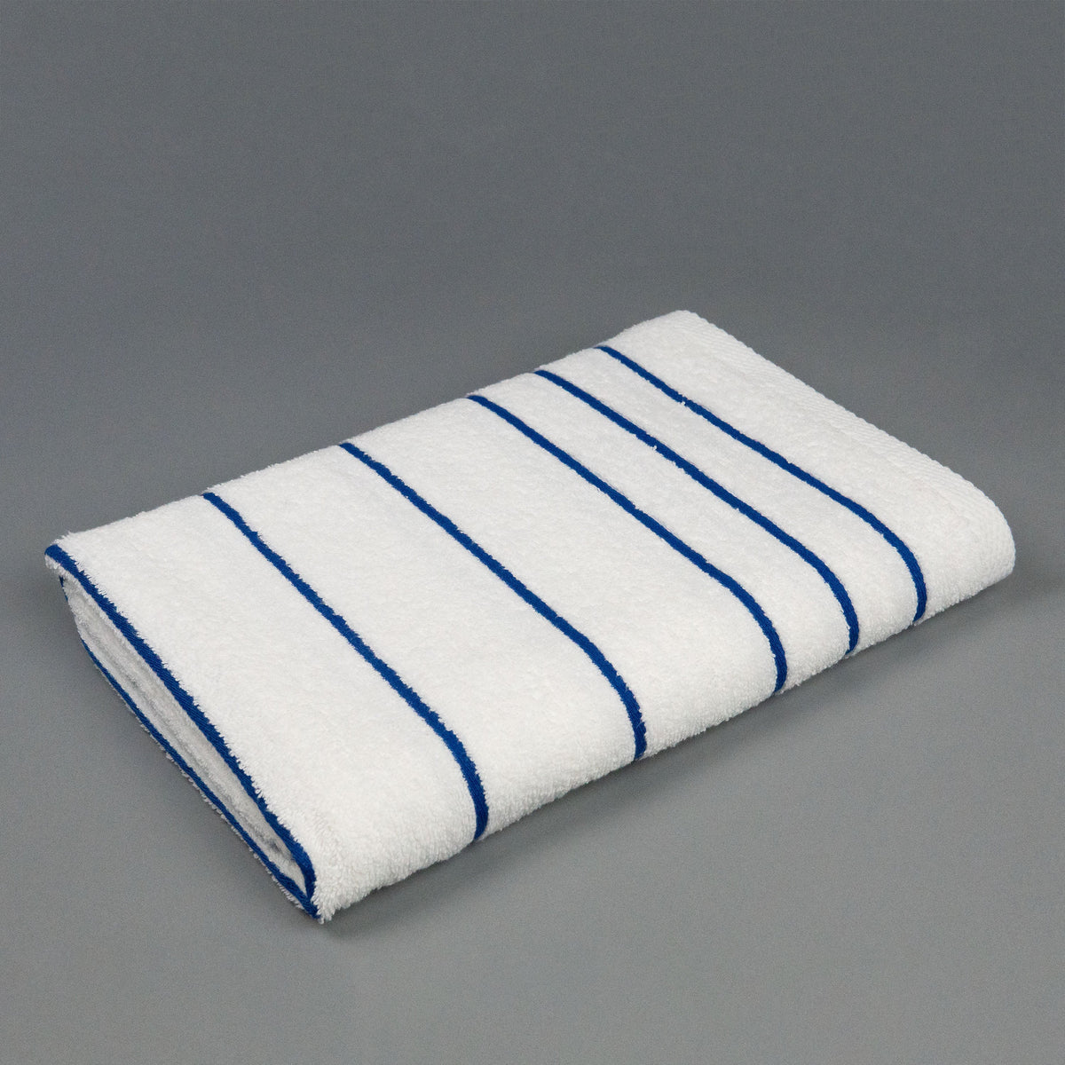 Pictured: The Blue Stripe Martex Resort Towel neatly folded and placed against a gray background.