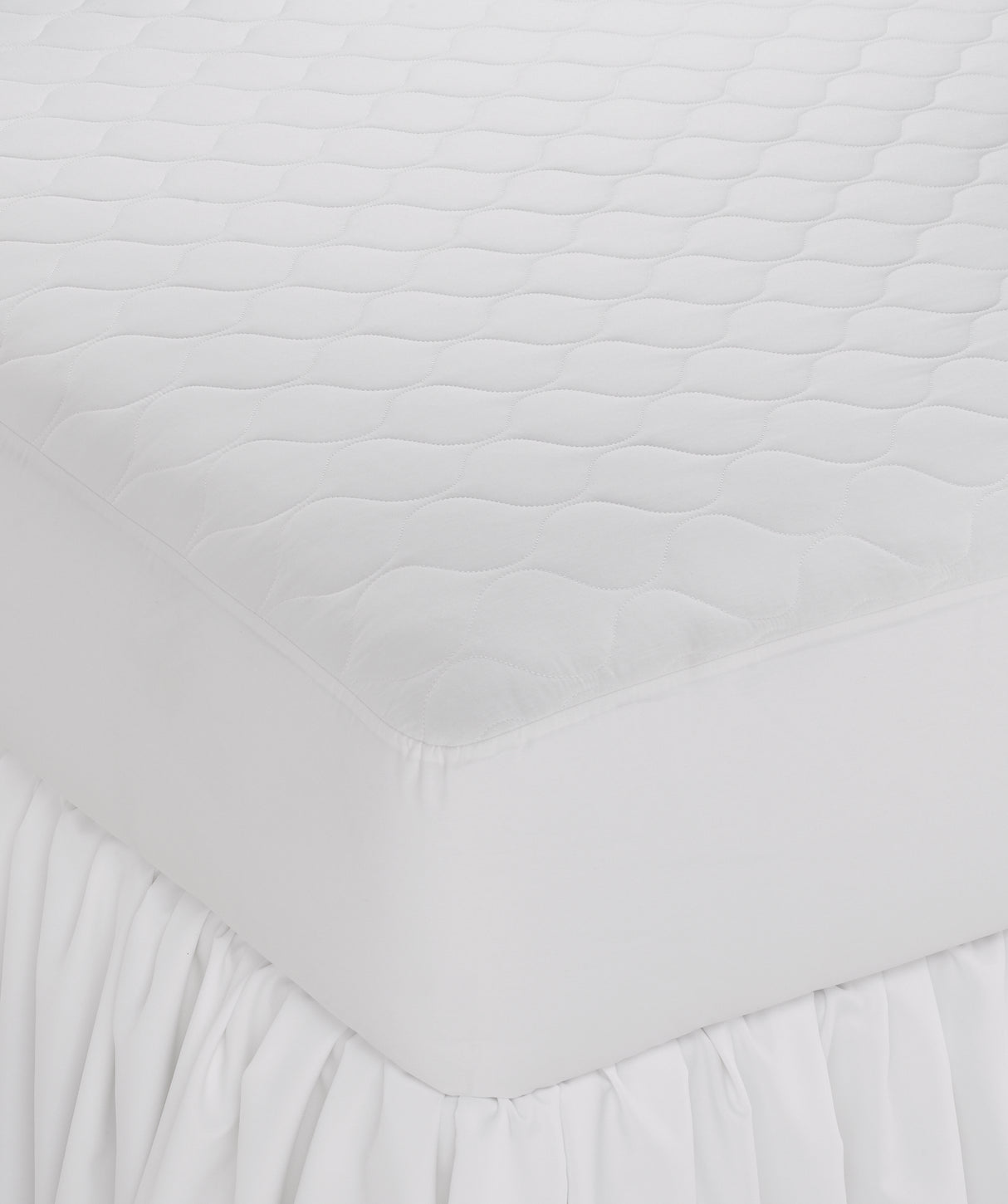 A white, fitted Martex Ultra Touch Mattress Pad on a bed, showcasing its quilted design and fitted skirt.
