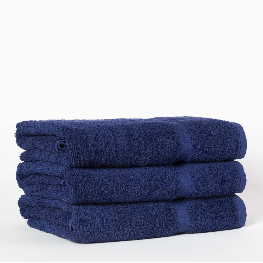 Pictured: Three neatly folded blue towels stacked on top of each other against a white background. The product featured are the Martex Towels in the shade "Navy".