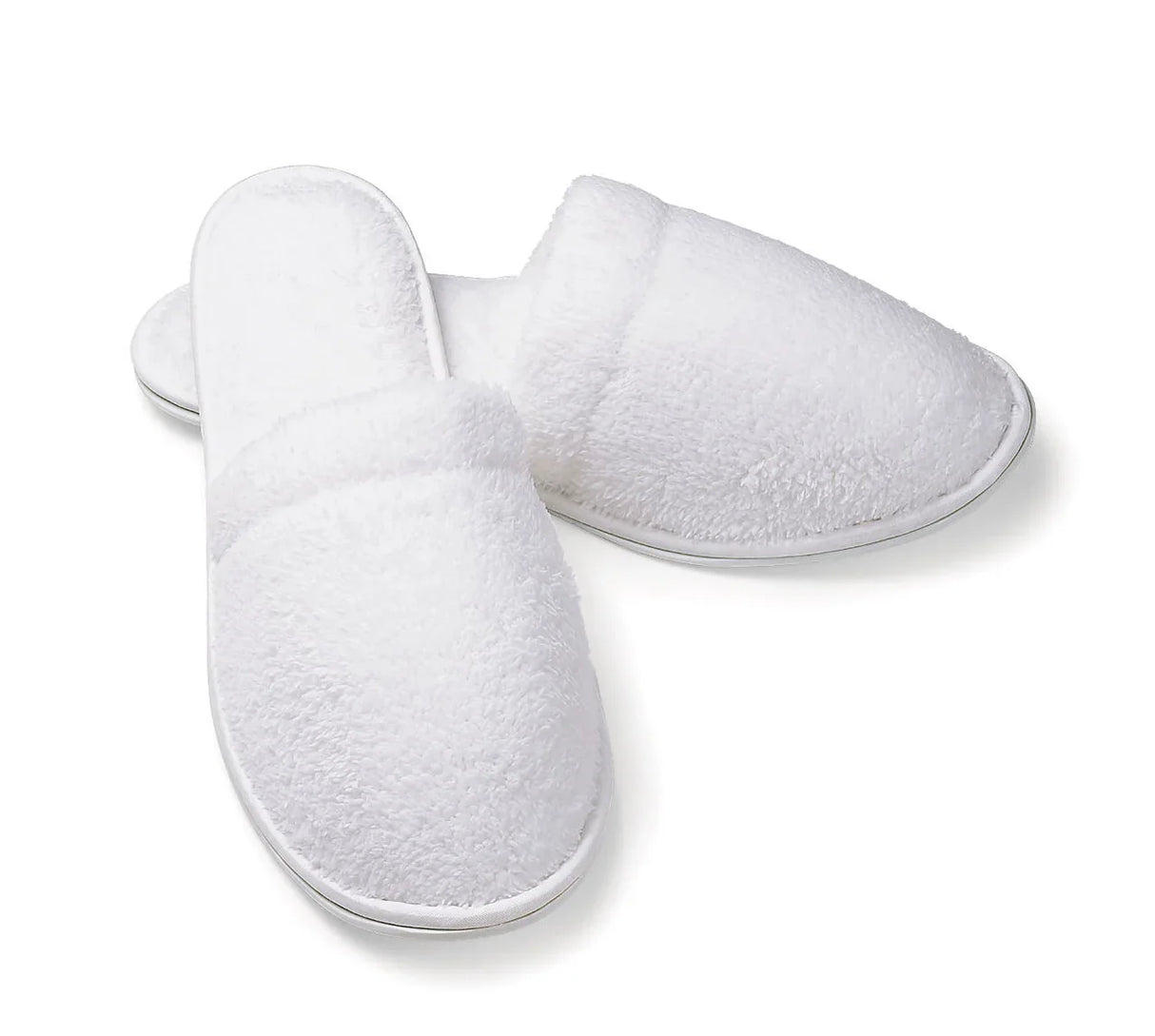 Product shot of some white fully slippers. The heels are crossed over andthey are made out of a microterry material. The background is plain white.