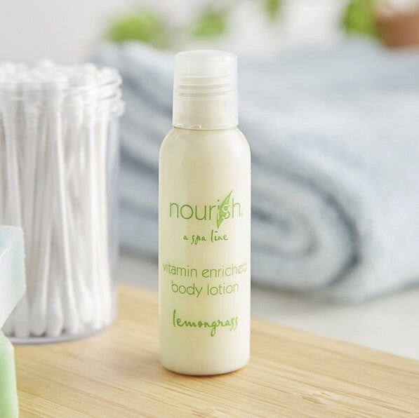 A body lotion bottle on a wooden shelf. It says on the front "Nourish, a spa line, vitamin enriched body lotion, lemongrass". Next to it is a container of q-tips.