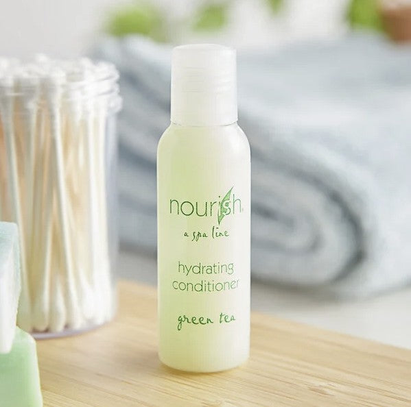 A standing conditioner bottle on a wooden shelf that says on the front; "Nourish, a spa line, hydrating conditioner, green tea." It is 1 fl. oz. or 30ml. Next to it is a container of q-tips.