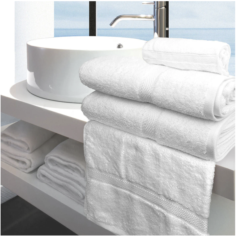 White towels neatly folded and placed on a shelf with a white sink and mirror in the background, showcasing a clean and elegant look.