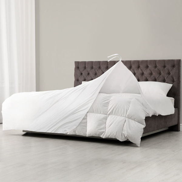 A white duvet insert is displayed on a bed with a brown headboard, showcasing its plush texture and color.
