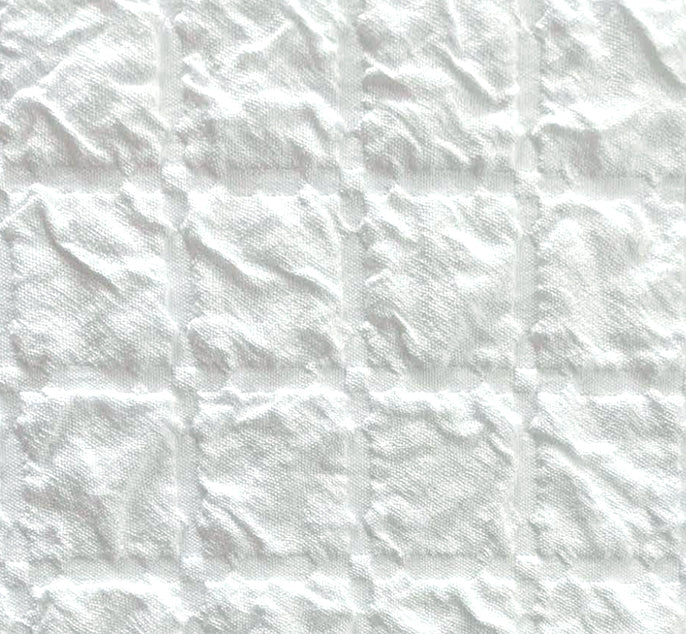 White textured fabric with a stitched grid pattern of square panels.