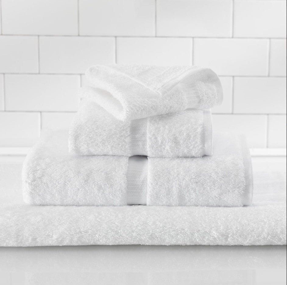 Stack of white towels on a white tiled wall background
