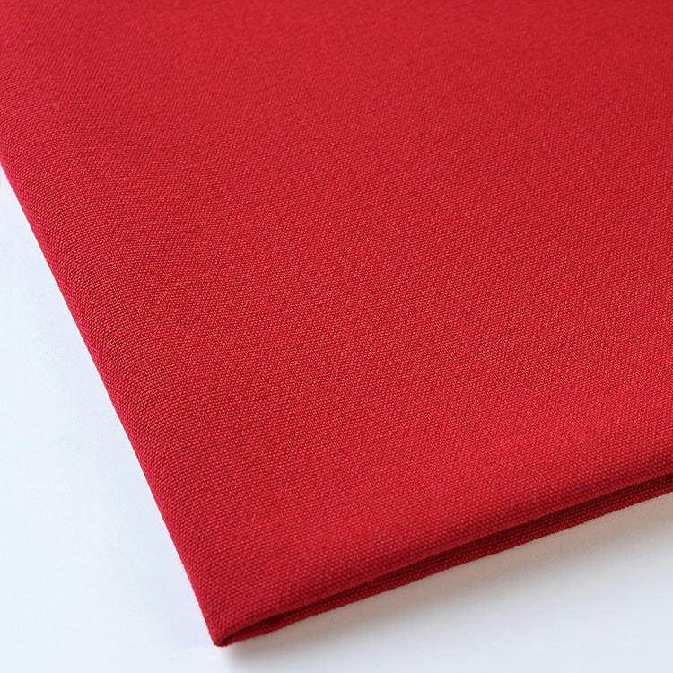 Product shot of a red polyester napkin tablecloth. Image is zoomed to emphasize texture and quality.
