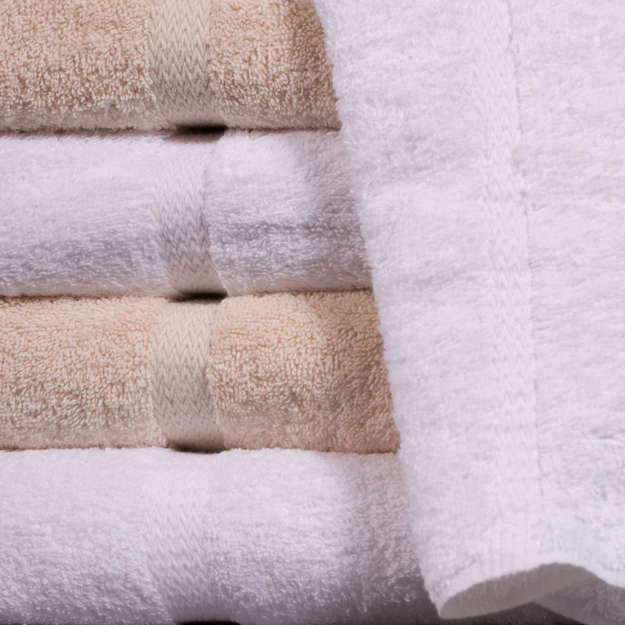 Stacked luxurious towels in both white and beige. Wholesale bulk by Boston Textile.