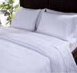 A set of white SuiteDream sheets displayed on a bed, showing a flat sheet and two pillowcases.