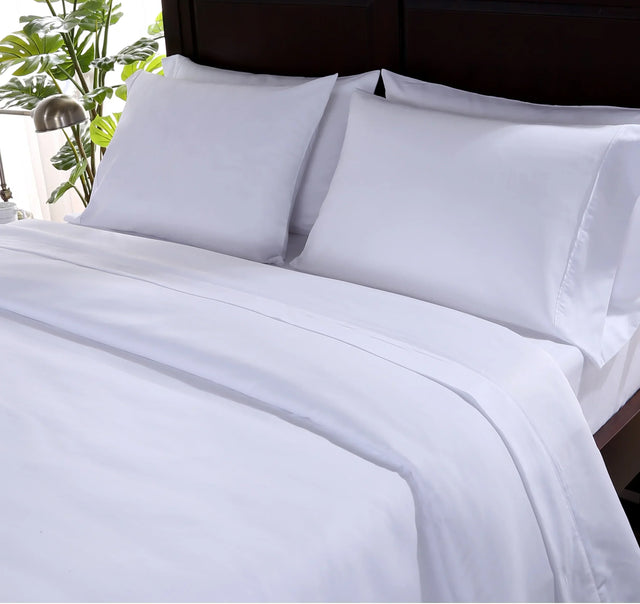 A set of white SuiteDream sheets displayed on a bed, showing a flat sheet and two pillowcases.