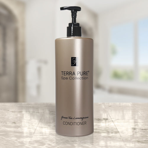 Product shot of the Terra pure spa collection hotel amenities conditioner. Dispenser model placed on a marble countertop in a bright lit room.