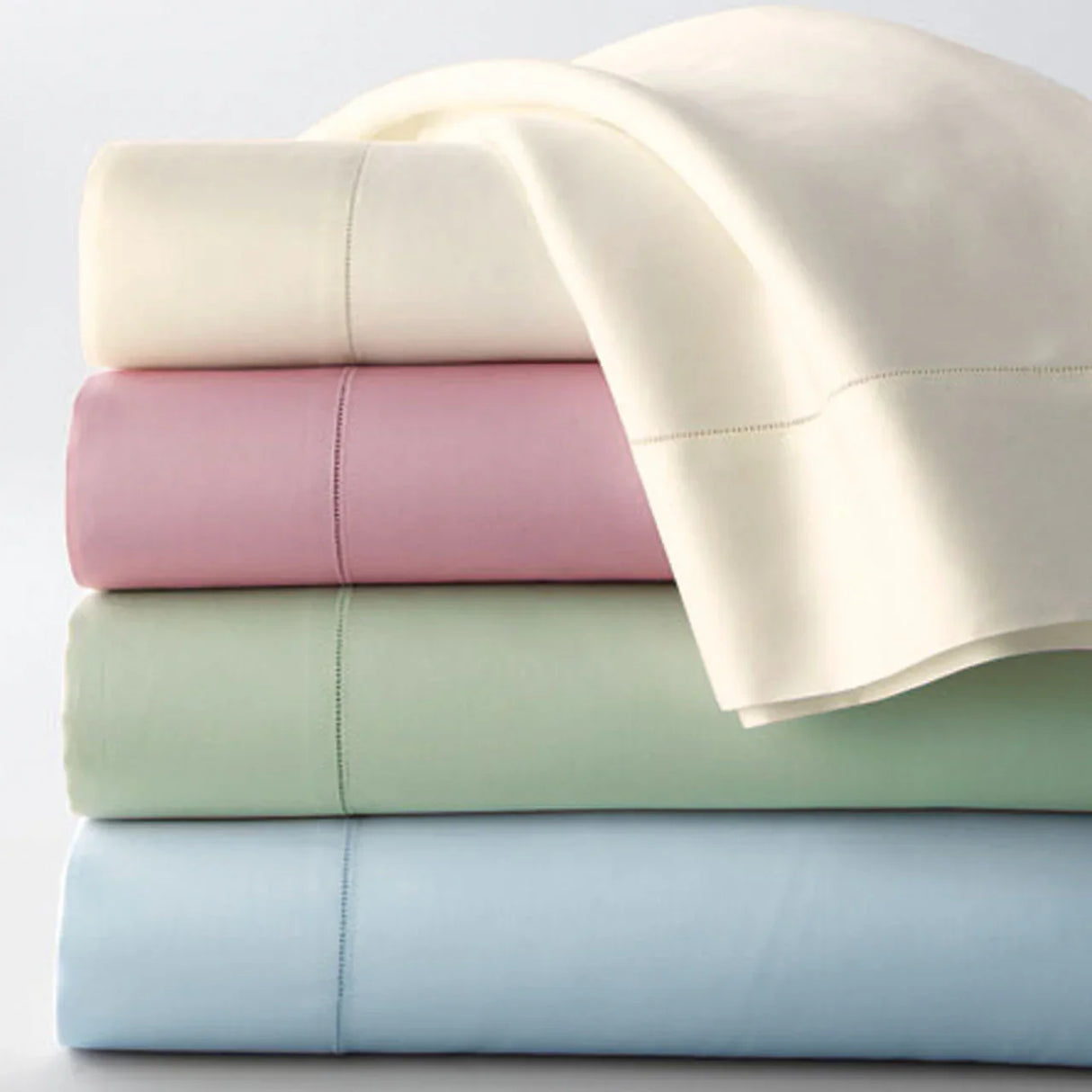 Product shot of multiple bed sheet sets in a variety of colors including yellow, pink, green, blue. Pastel colors. White background.