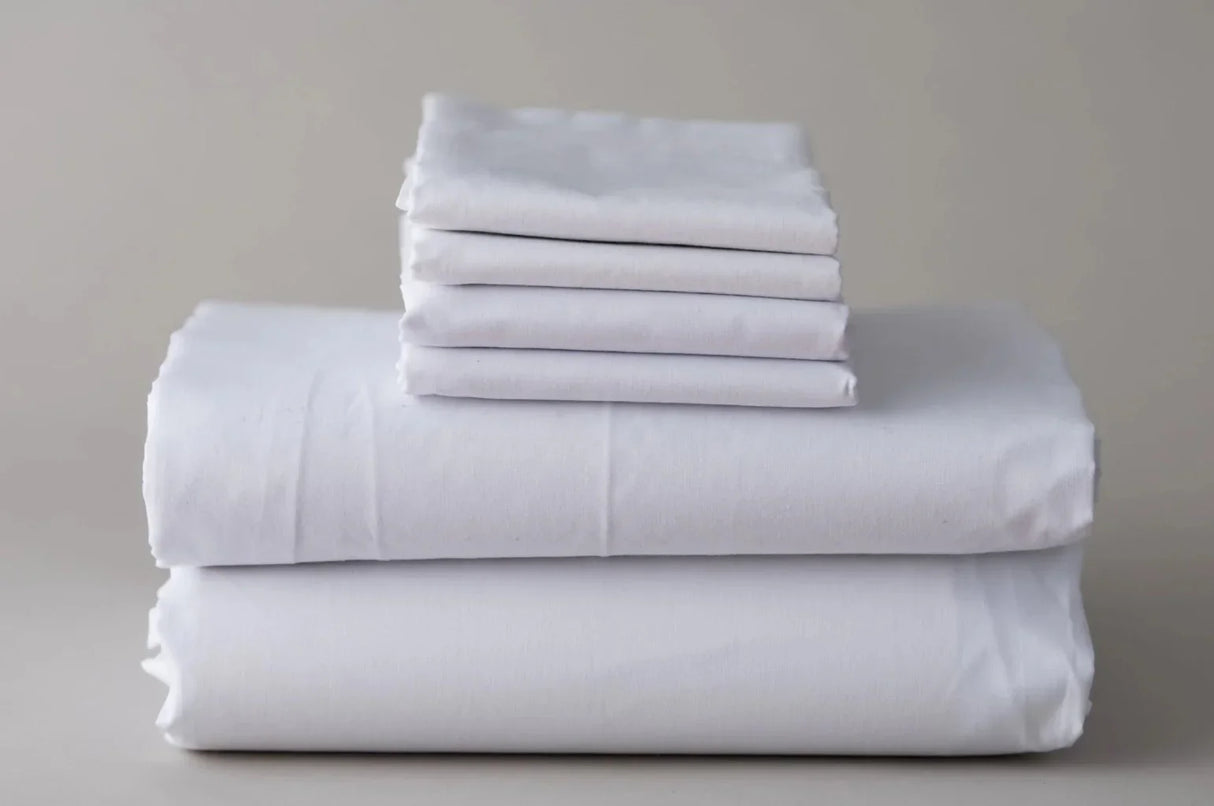 Product shot of white bed sheet set. Features pillowcases, fitted sheets, flat sheets and duvet covers. High quality bed linen. White background.