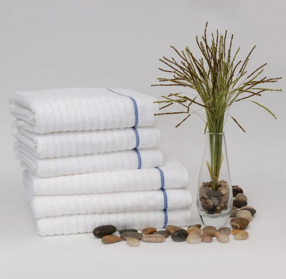 Product showcases a stack of pool towels by 1888 Mills. They are white with a singular blue stripe at the end.