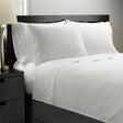 White bedding set on a bed with a nightstand in the foreground