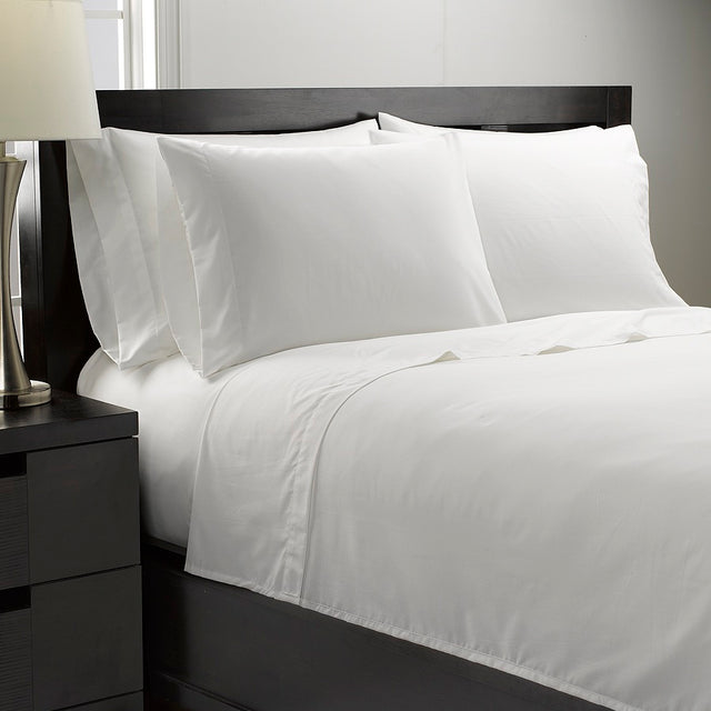 White bedding set on a bed with a nightstand in the foreground