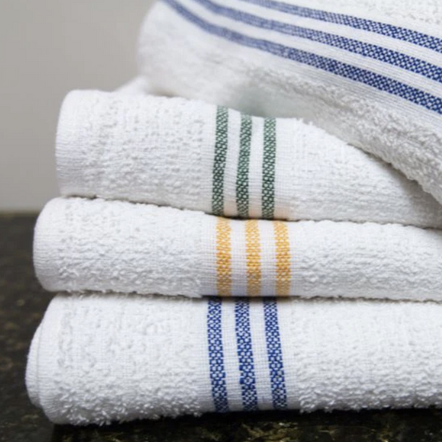 Stack of white towels with colorful stripes on a dark surface