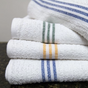 Stack of white towels with colorful stripes on a dark surface