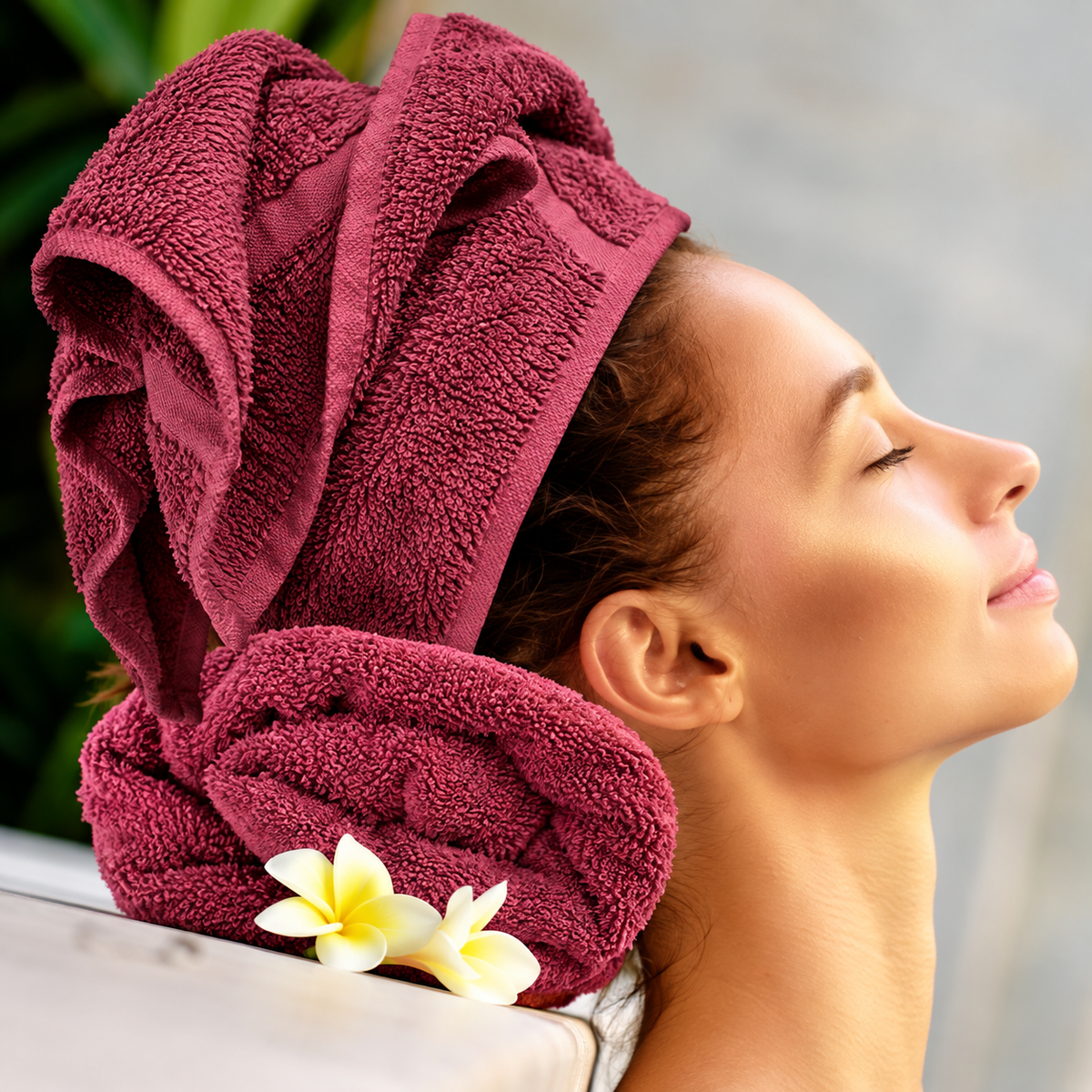 Pictured: Model leaning back on a neatly rolled towel, with their hair wrapped in the same colored towel. This is the Oxford Salon and Spa Towel in the shade Burgundy.
