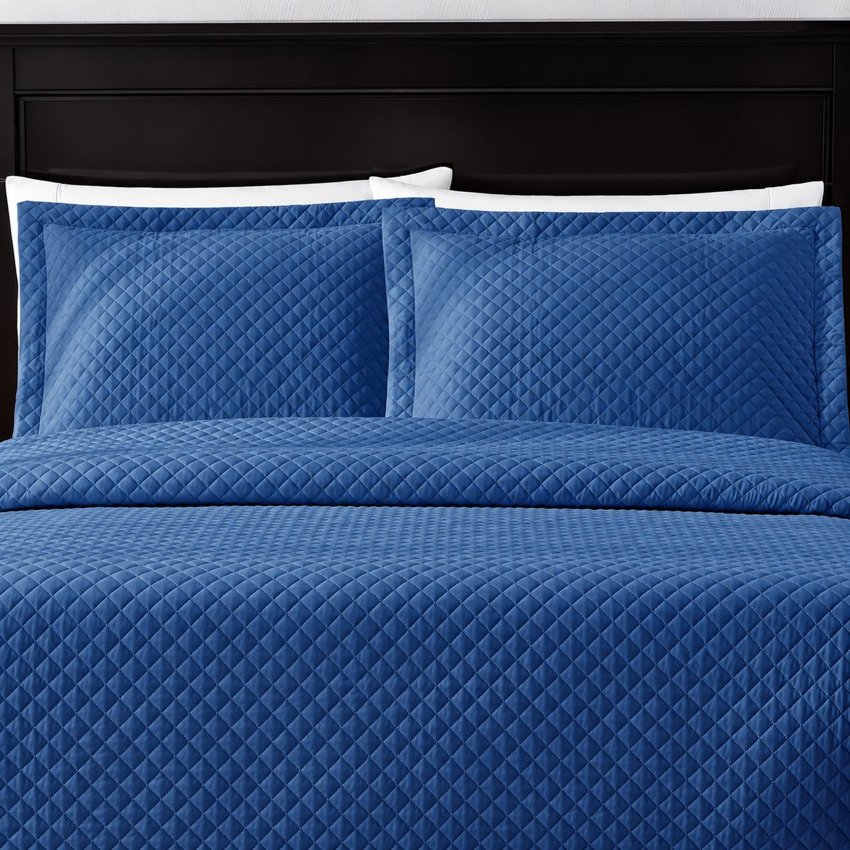 Pictured: Blue bedding on a dark wood bedframe. The bedding features the Radiance Diamond Quilted Sham, which has a diamond stitch creating a textured pattern.