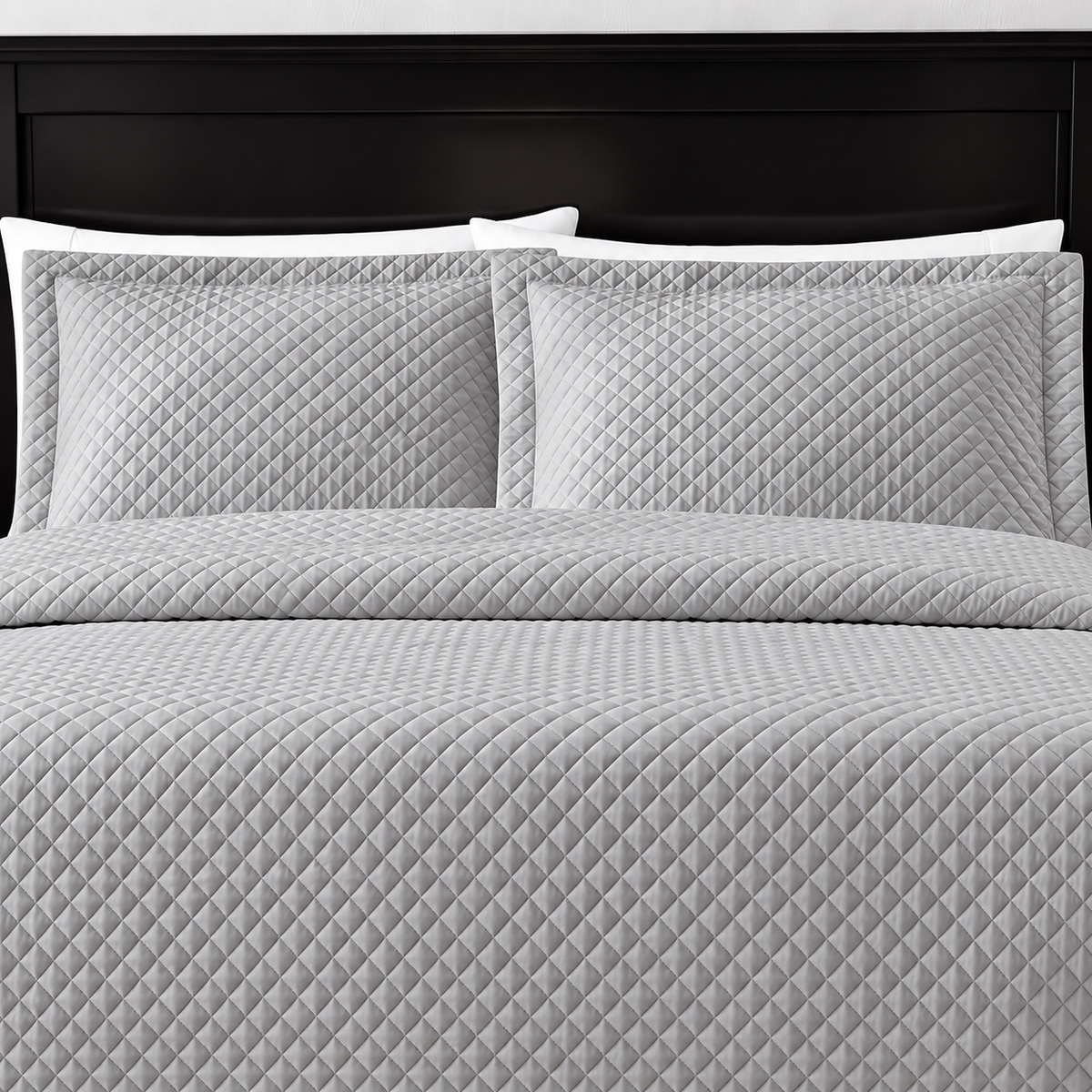 Pictured: Grey bedding on a dark wood bedframe. The bedding features the Radiance Diamond Quilted Sham, which has a diamond stitch creating a textured pattern.