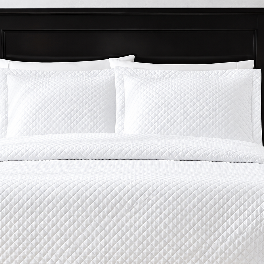 Pictured: White bedding on a dark wood bedframe. The bedding features the Radiance Diamond Quilted Sham, which has a diamond stitch creating a textured pattern.