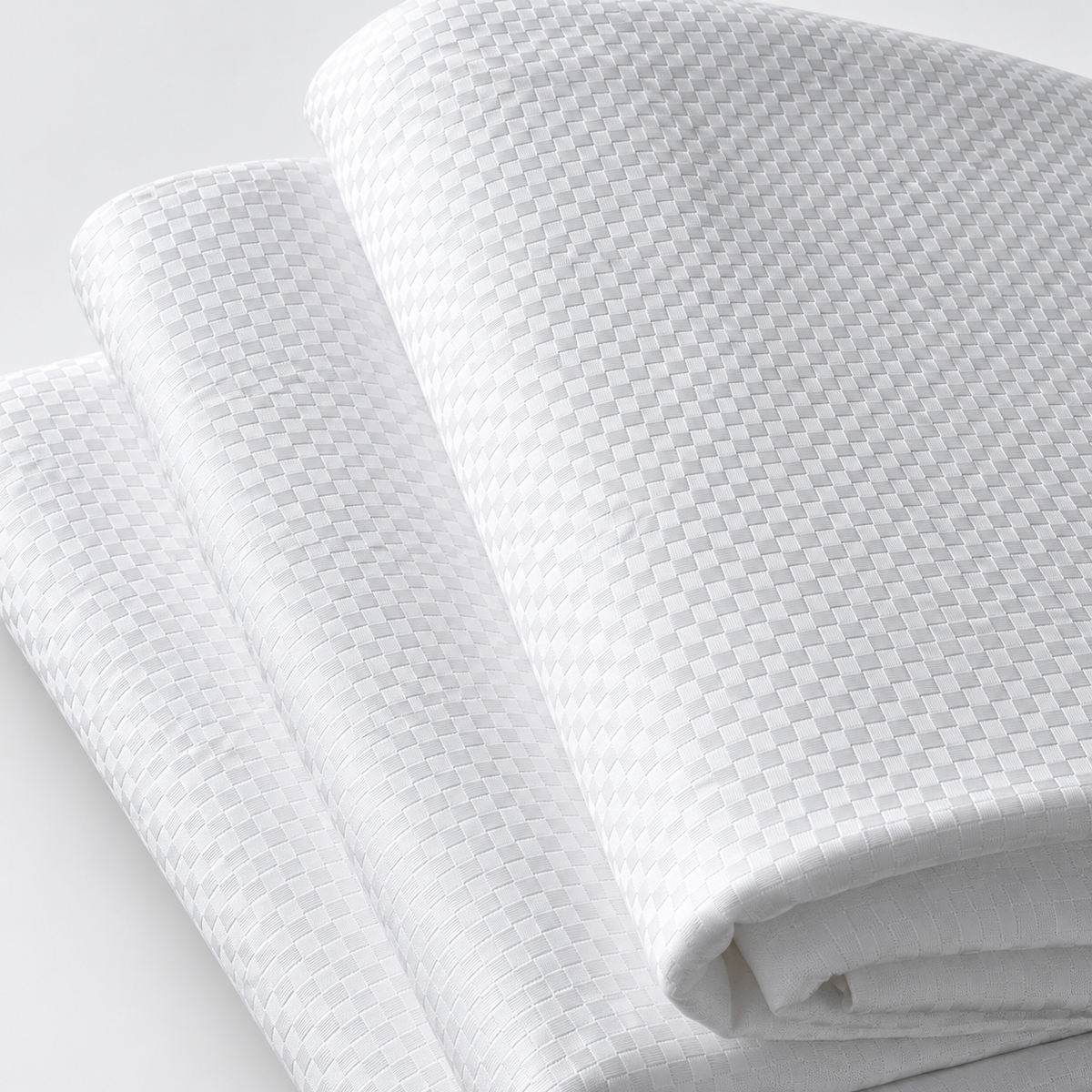 Pictured: Three white checkered sheets neatly folded and stacked on top of each other against a white background.
