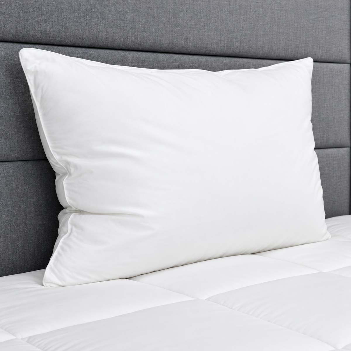 Pictured: White pillow on a white comforter against a grey fabric headboard.