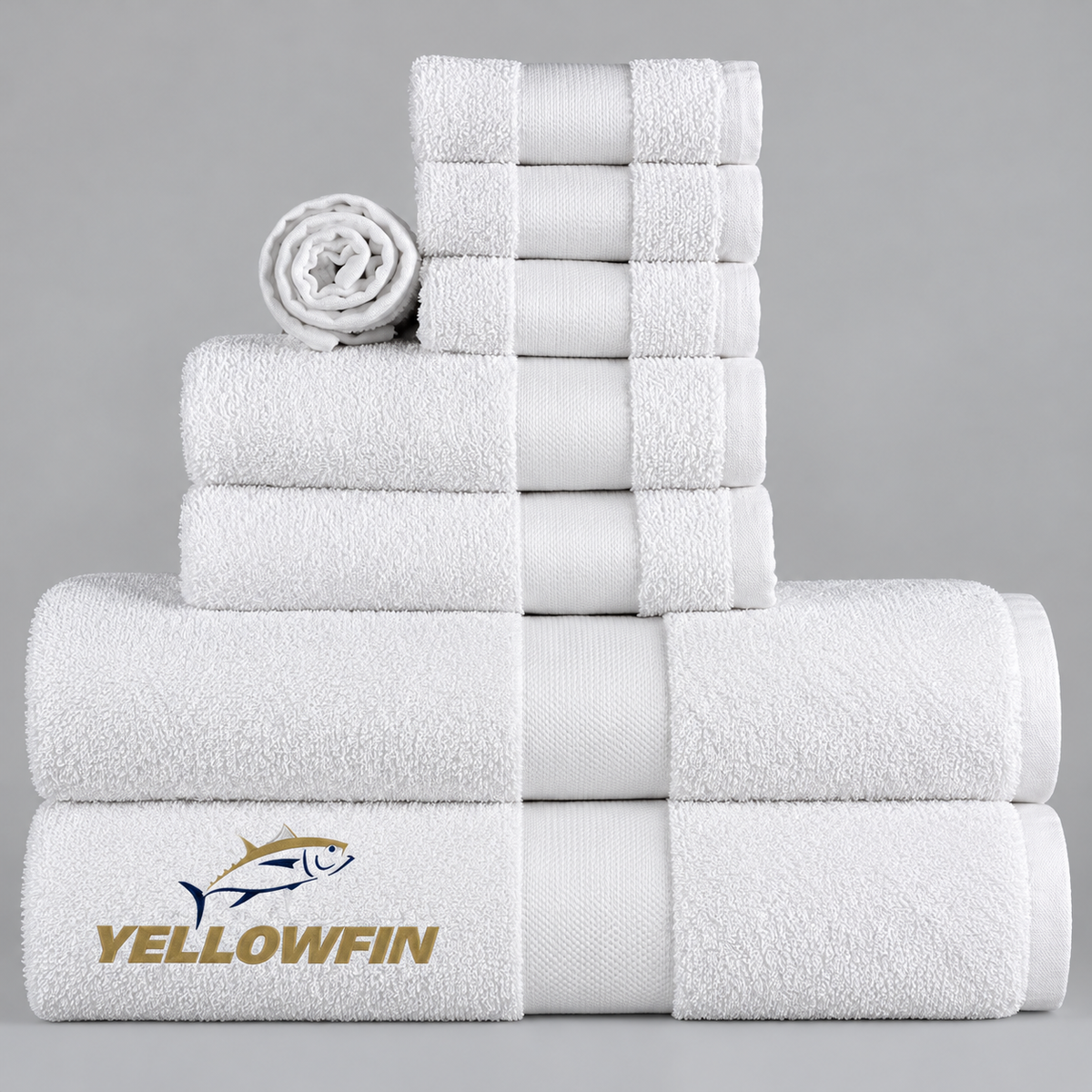 Pictured: White towels with a cam border in the center. The towels are neatly folded and stacked according to size. In the bottom left corner is the YELLOWFIN logo.